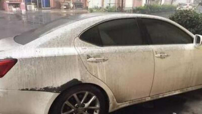 Sebuah mobil menjadi korban hujan hitam di China.