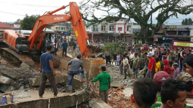 Aparat Kepolisian dan TNI mengerahkan alat berat untuk mengevakuasi tiga warga yang terjebak reruntuhan rumah toko akibat gempa bumi di Pidie Jaya, Aceh, pada Rabu, 6 Desember 2016.