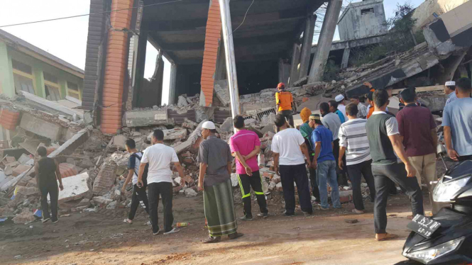 Warga mengamati bangunan yang rusak akibat gempa di Aceh.