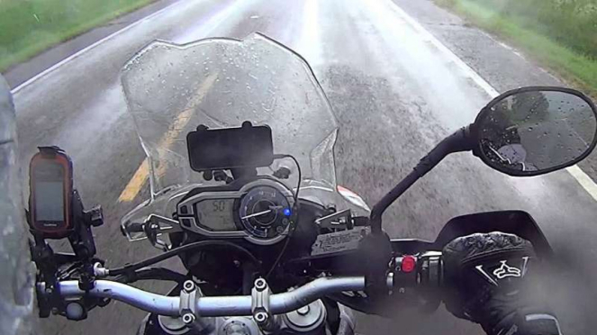 Ilustrasi mengendarai motor saat hujan.