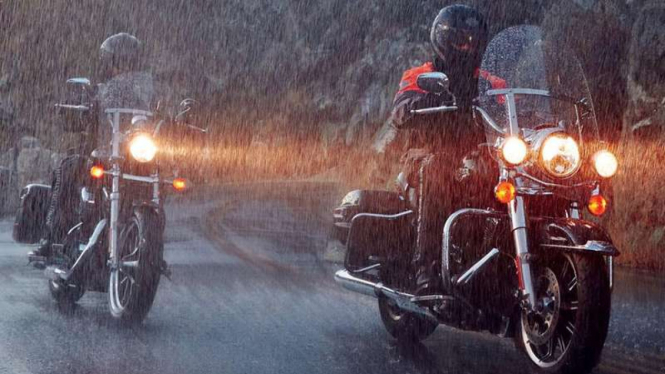 Ilustrasi mengendarai motor saat hujan.