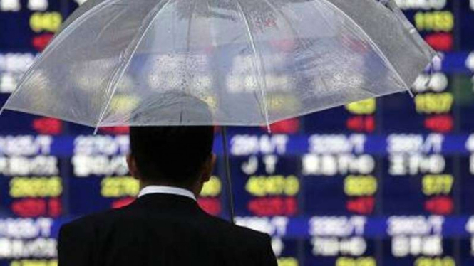 Seorang warga mengamati papan di bursa saham Jepang. 