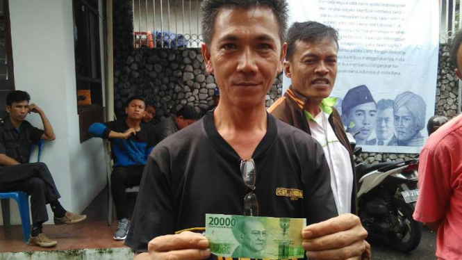 Robby, seorang buruh bangunan, memperlihatkan uang Rp20.000 yang bergambar Sam Ratulangi setelah mengantre menukarkan uang di kantor Bank Indonesia Kota Manado pada Rabu, 21 Desember 2016.