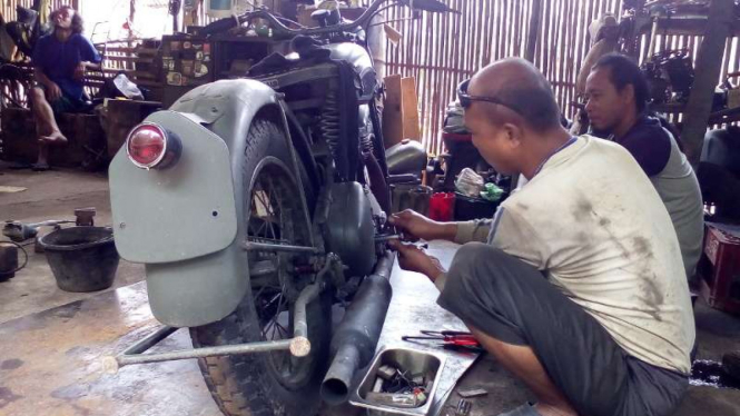 Mujiyanto sedang merakit motor tua.
