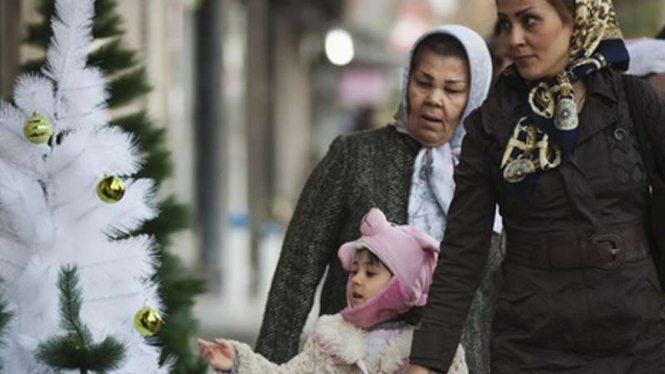 Seorang anak bersama ibunya melihat dekorasi pohon Natal di Teheran, Iran.