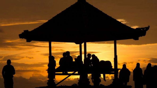Turis menyaksikan matahari terbit di kawasan wisata Pantai Sanur, Bali.