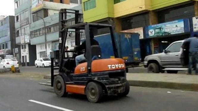 Forklift melintas di jalan raya.