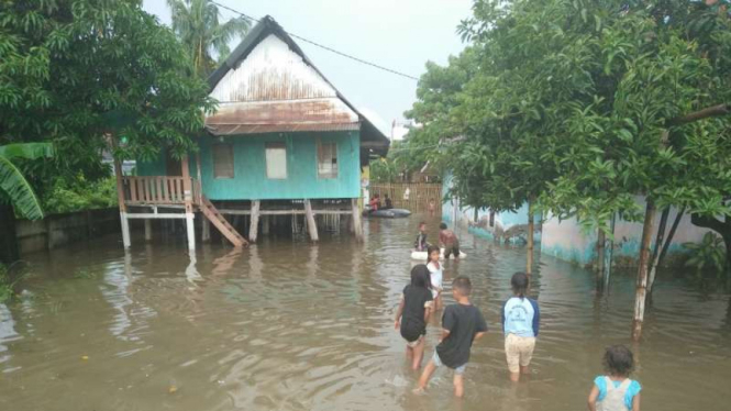 Anak-anak bermain di air yang menggenangi pemukiman warga di Jalan Jokowi atau di Kelurahan Maccini Sombala, Kecamatan Tamalate, Makassar, Jumat (6/1/2017).