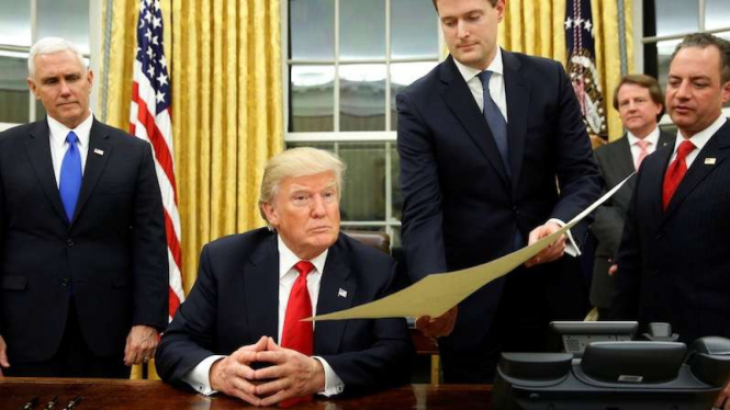 Presiden baru AS, Donald Trump, bersiap tanda tangan sejumlah dokumen resmi tak lama setelah dilantik, 20 Januari 2017.