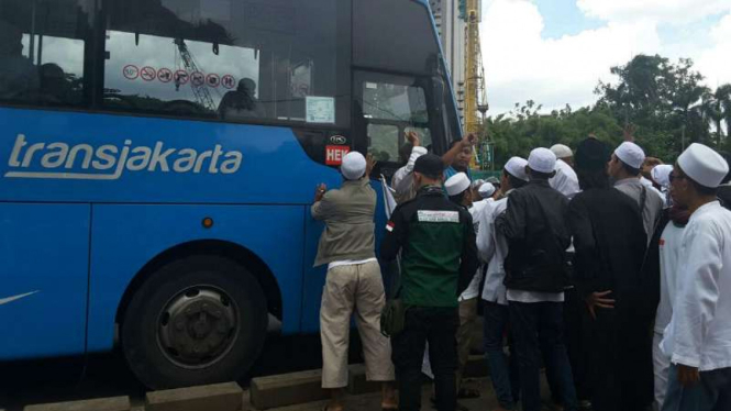 Pendukung Rizieq Sihab mengevakuasi pedagang yang tertabrak Transjakarta.