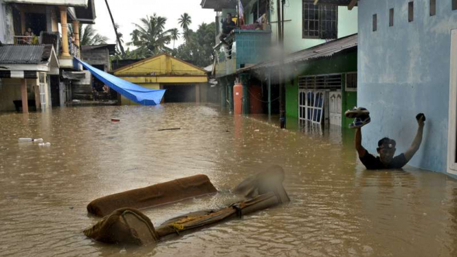 Warga berjalan menembus banjir yang menggenangi perumahan di Kampung Mahawu, Singkil, Tuminting, Manado, Sulawesi Utara, Kamis (26/1/2016)