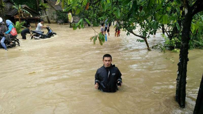 Seorang warga di Banten Selatan yang menjadi korban bencana banjir saat berusaha melintas di genangan air, Kamis (9/2/2017)