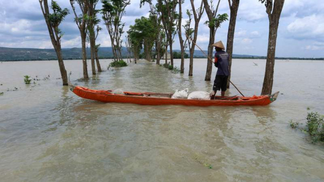 Seorang warga dengan perahu menyeberang jalan yang terendam banjir luapan Bengawan Solo di Desa Kanorejo, Kecamatan Rengel, Kabupaten Tuban, Jawa Timur, Minggu (5/2/2017)