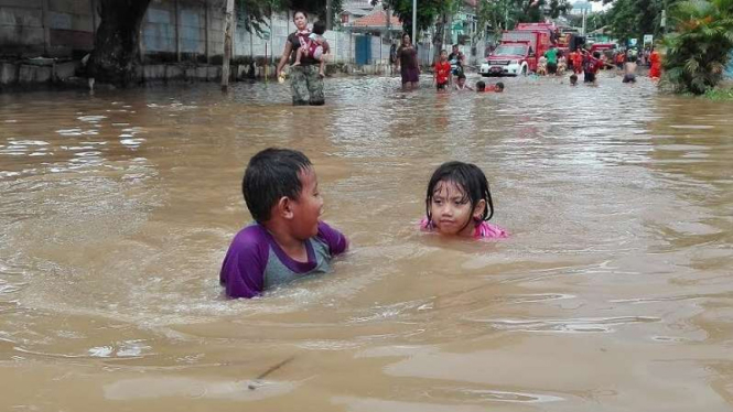 Dua anak bermain air di lokasi banjir Bukit Duri, Jakarta Selatan.