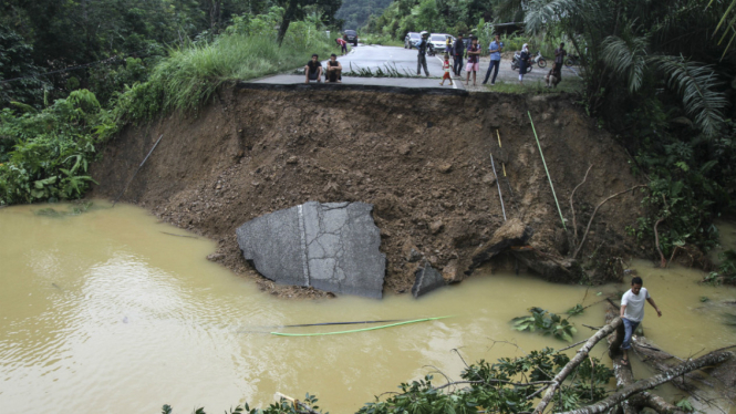 Warga melihat kondisi jalan lintas Provinsi Riau dan Sumatera Barat yang putus akibat banjir di Desa Tanjung Balit, Sumatera Barat, Jumat (3/3). 