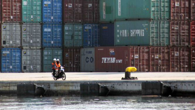 Dua pekerja di Pelabuhan Peti Kemas Tanjung Priok tengah melintas dengan sepeda motor.