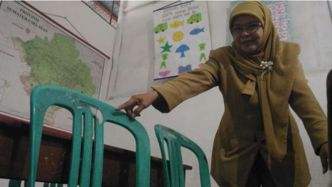 Harisah (50), Kepala SD MI Duku Kota Palembang menunjukkan lubang di kursi plastik yang tertembak peluru, Senin (13/3/2017)
