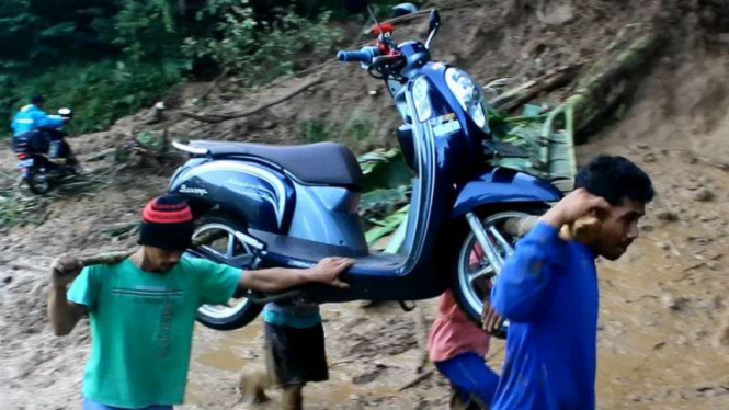 Warga menggotong sepeda motor melewati jalur terputus longsor di Cisewu, Garut