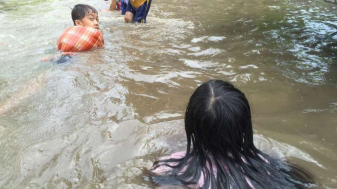 Anak-anak sedang bermain air saat banjir terjadi di Manado, Sulawesi Utara, Senin 20 Maret 2017.