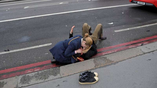 Seorang warga coba selamatkan korban serangan di London, 22 Maret 2017.