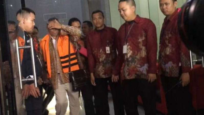 Direktur Utama PT PAL Indonesia, Muhammad Firmansyah Arifin (oranye), tutupi wajahnya saat digelandang ke tahanan, Jumat malam, (31/3/2017)..