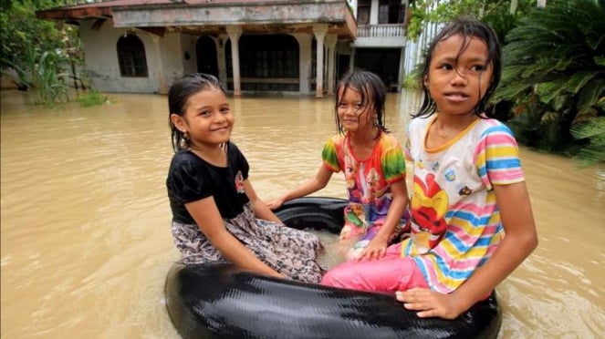 Ilustrasi sejumlah anak mengarungi banjir.