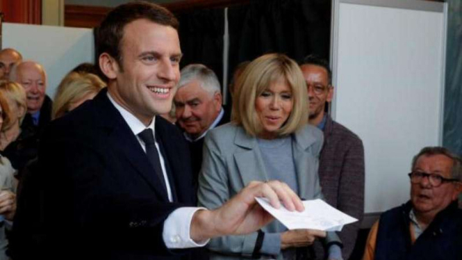 Macron bersama istrinya, Brigitte Trogneux, saat pencoblosan.