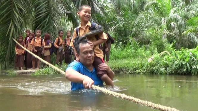 Zulkarnaen Siregar menyeberangkan anak-anak melewat sungai untuk ke sekolah setiap hari Desa Ulu Mahuam, Kecamatan Silangkitang, Kabupaten Labuhanbatu Selatan, Sumatera Utara, pada Selasa, 2 Mei 2017.