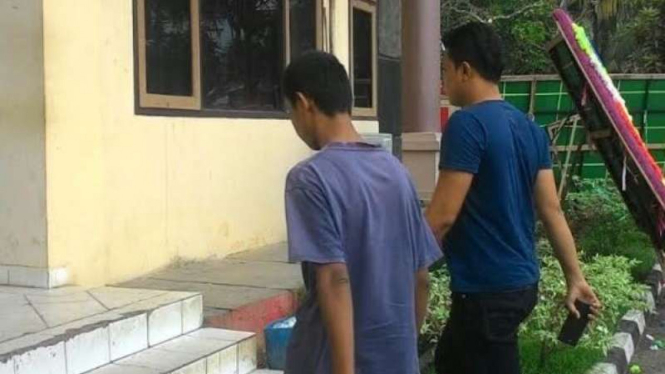 Ujang (kiri), pelaku pelecehan seksual atas murid SMP di Palembang, digiring ke kantor polisi.