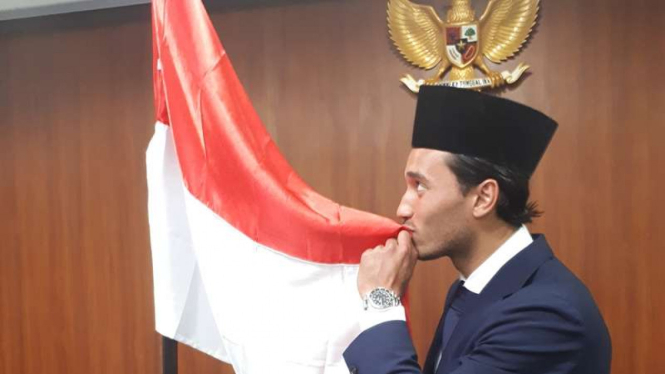 Ezra Walian mencium bendera Indonesia saat pengambilan sumpah