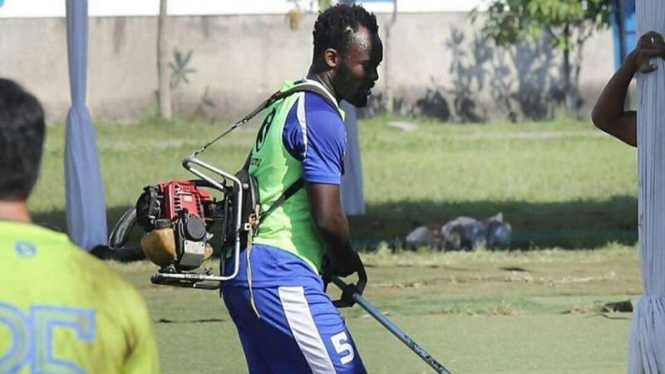 Pemain Persib Bandung, Michael Essien menggotong mesin pemotong rumput