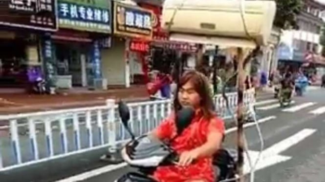 Seorang perempuan naik motor ber-AC.