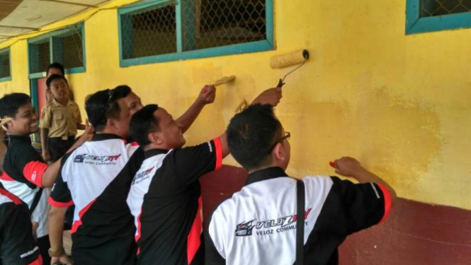 Anggota Velozity membantu cat dinding sekolah di Lampung.