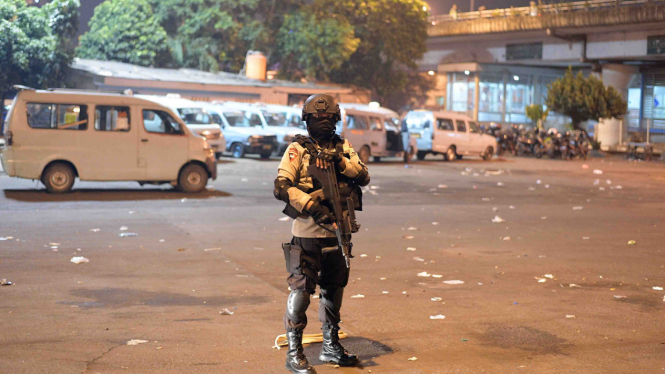 Seorang polisi bersenjata lengkap sedang berjaga di lokasi kejadian ledakan bom di Kampung Melayu, Jakarta.