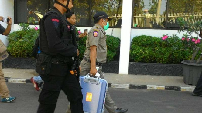 Seorang petugas dikawal personel Brimob membawa koper setelah penggeledahan di kantor Dinas Peternakan Jawa Timur di Surabaya pada Rabu, 7 Juni 2017.