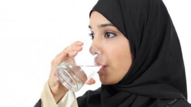 Wanita minum air putih.
