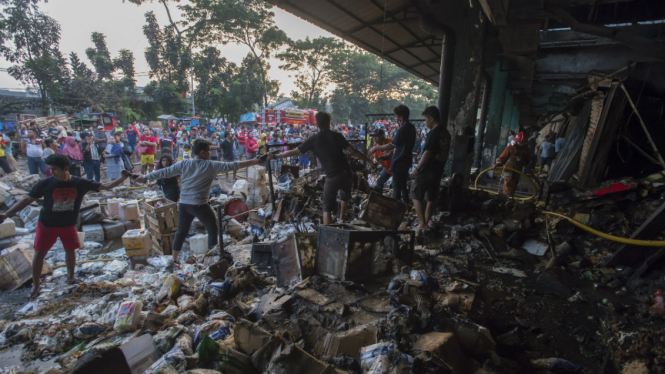 Sejumlah pekerja memindahkan barang dagangan yang selamat dari kebakaran yang melanda sejumlah kios sentra bumbu dapur dan rempah-rempah di Blok C1 Pasar Induk Kramat Jati, Jakarta Timur, Senin (12/6).