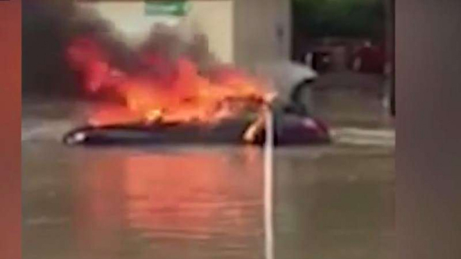 Mobil terbakar saat terjebak banjir.