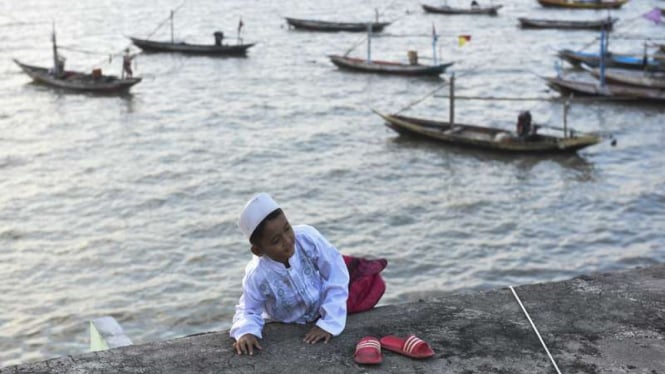 Seorang anak menuruni sebuah bangunan di kawasan Masjid AL-Mabrur usai Salat Idulfitri, Kenjeran, Surabaya, Jawa Timur, Minggu (25/6/2017)