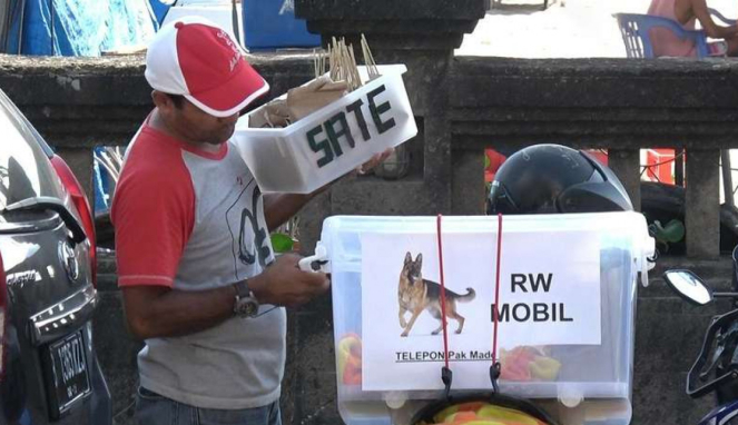 Seorang penjaja sate daging anjing di menjual dagangannya di suatu kawasan wisata.