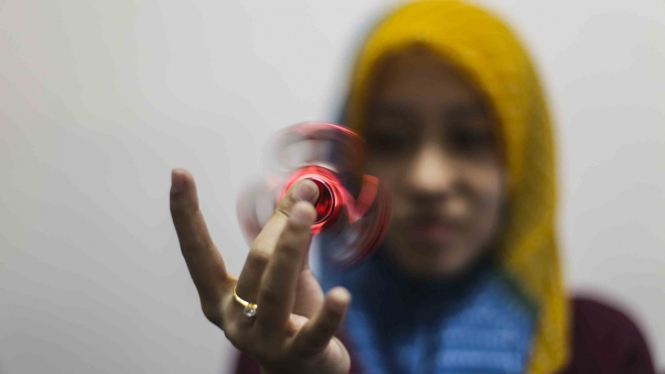 Seorang wanita sedang memainkan finger spinner di Jakarta.
