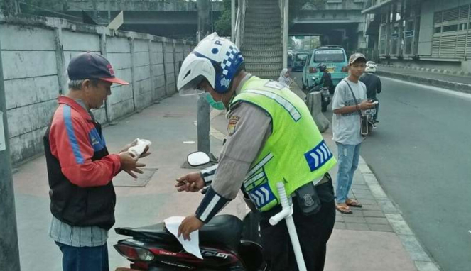 Polisi tilang seorang warga yang bawa sepeda motornya di atas trotoar Jatinegara, Jakarta Timur.