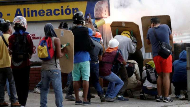 Warga Venezuela melindungi diri dari serangan gas airmata.