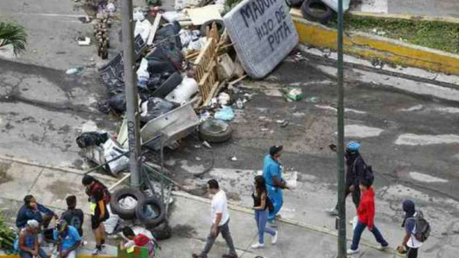 Masyarakat berjalan melewati barikade usai terjadi bentrokan di Caracas, Venezuela 