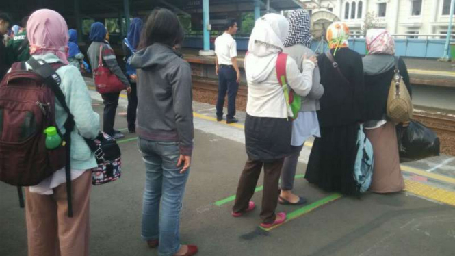 Penumpang berbaris di garis antre naik KRL di Stasiun Juanda, Jakarta Pusat.