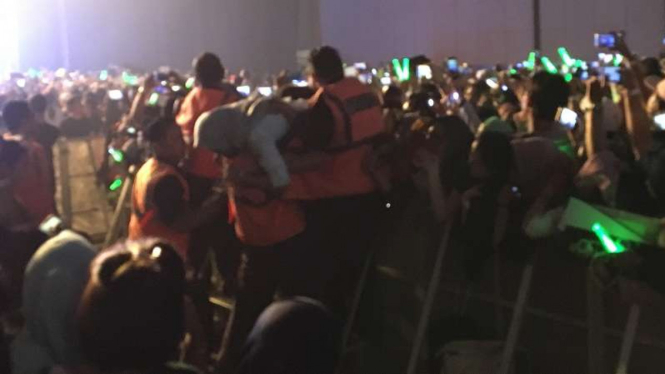 Petugas medis mengevakuasi penonton NCT 127 yang pingsan.