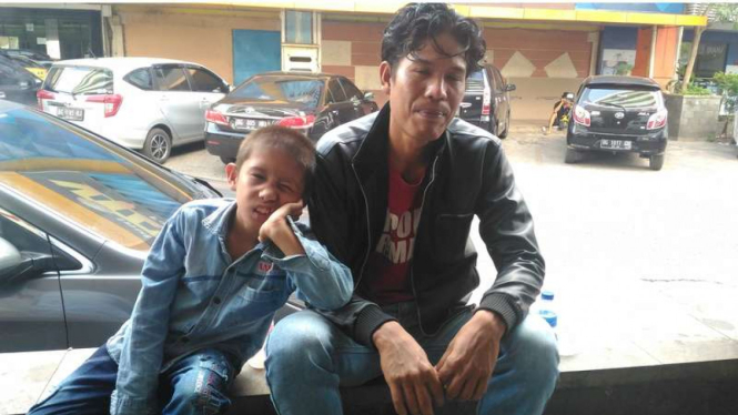 Desen (9), bocah berkelamin ganda asal Sumatera Selatan bersama ayahnya Herlidi (37), Kamis (10/8/2017)