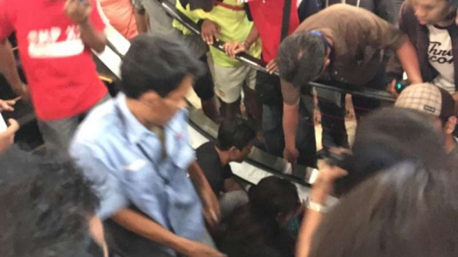 Petugas dan pengunjung berusaha membebaskan kaki bocah yang terjepit eskalator.