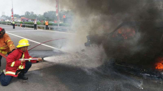 Petugas  memadamkan api yang membakar mobil di Tol Jagorawi