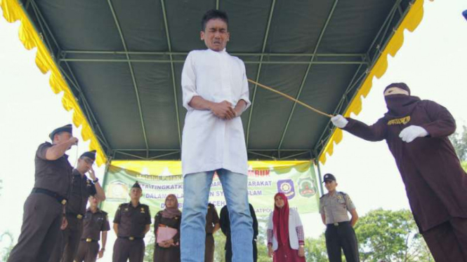 Algojo mencambuk seorang pelanggar syariat Islam di depan umum di Masjid Agung Al Munawarah Kota Jantho, Aceh Besar, Aceh, pada Jumat, 25 Agustus 2017.